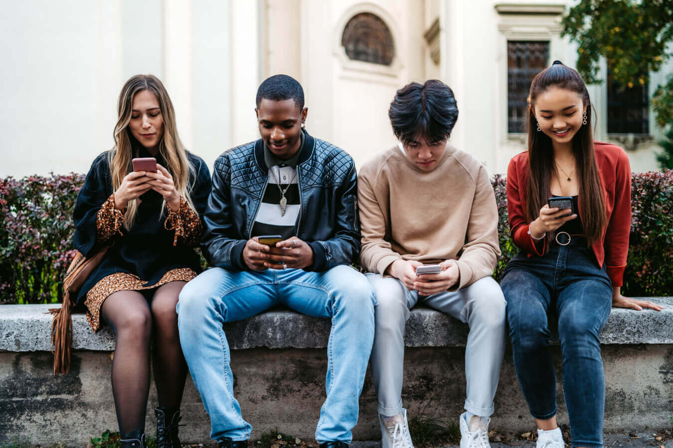 Un groupe d'adolescents assis en train de regarder leur téléphone.